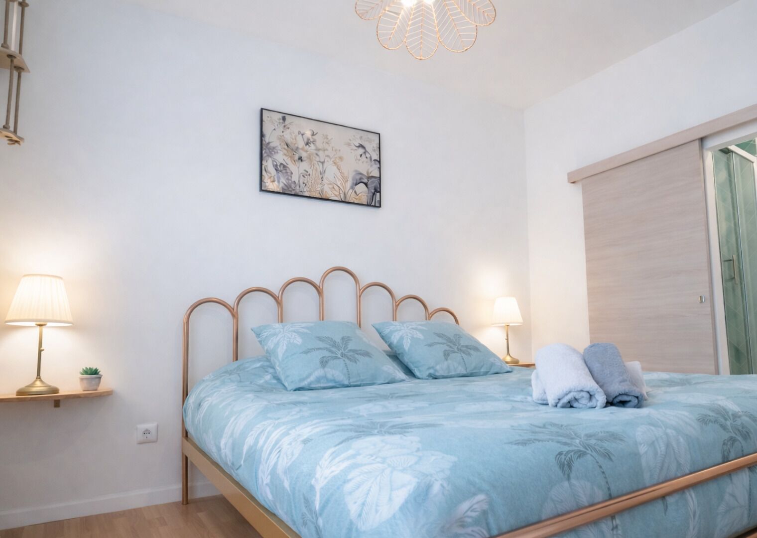 Quarto com cama, quadro na parede, abajures e janela com cortina.