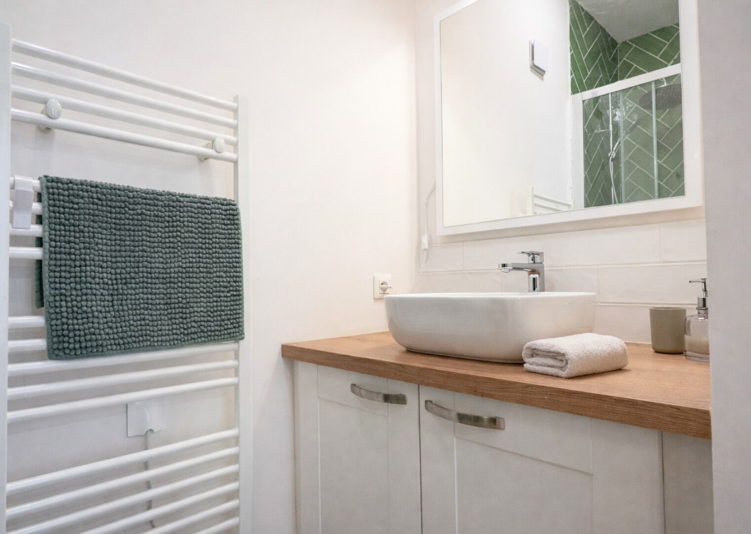 Un baño con un lavamanos blanco, una toalla verde y una toalla blanca sobre el mostrador.