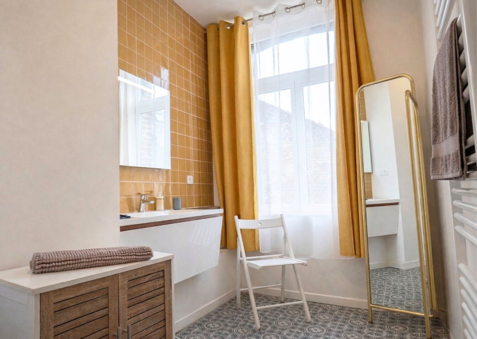 A bathroom with a white sink, mirror, and a chair.