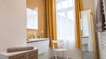 A bathroom with a white sink, mirror, and a chair.