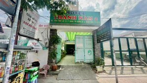 A hotel entrance with a green gate, a signboard for Hotel Thanh Nam 2, and a small shop with various items on display. - Thanh Nam Hotel - by Bay Luxury (Ho Chi Minh City)
