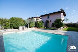 Une piscine à l’eau d’un bleu cristallin, entourée d’un chemin de pierre et d’une végétation luxuriante.