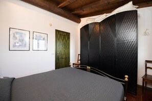 Une chambre avec un grand lit, une porte verte et deux tableaux encadrés accrochés au mur.
