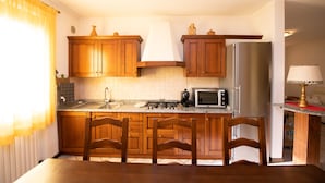 Una cocina con gabinetes de madera, un refrigerador de acero inoxidable, un microondas y una estufa a gas.