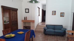 A dining area with a table set for two, a sofa, and a staircase leading to another room. - 2 Bedroom Apartment in Specchiolla (Specchiolla)