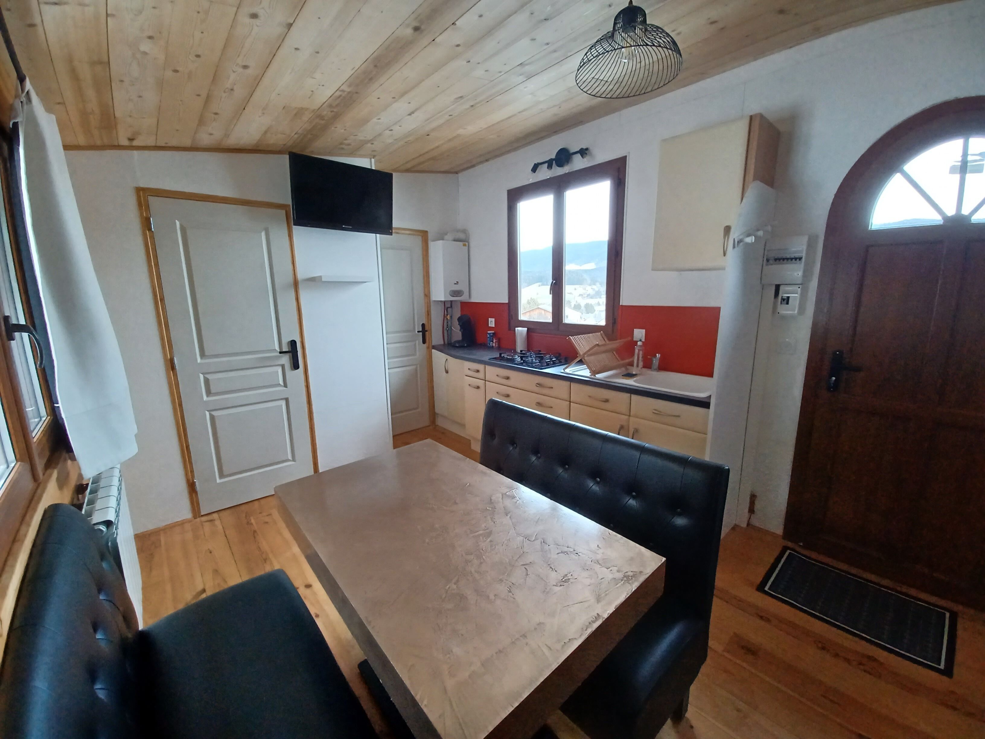 Una cocina acogedora con armarios de madera, una mesa de comedor y un ventanal grande.