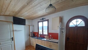 A kitchen with a wooden ceiling, a dining table, and a view through a window. - Tiny House in Méaudre in the heart of nature (Vercors plateau) (Autrans-Méaudre en Vercors)