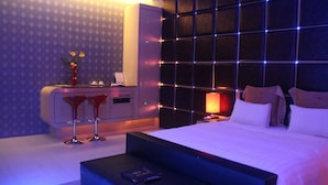 Una habitación de hotel moderna con una cama grande, una mesita de noche, un escritorio con una silla y un jarrón decorativo.