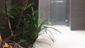 Un baño moderno con ducha de vidrio, una composición de plantas y una estructura de madera.