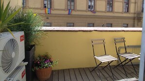 Parvekkeella on kaksi tuolia, ruukkukasvi ja ilmastointilaite.