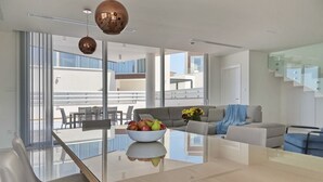 Ett modernt vardagsrum med ett matbord i glas, en soffa och ett soffbord med frukt på.