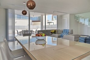 Relax in this inviting living area with a glass dining table and comfortable sofa, perfect for enjoying the view from the adjacent balcony.