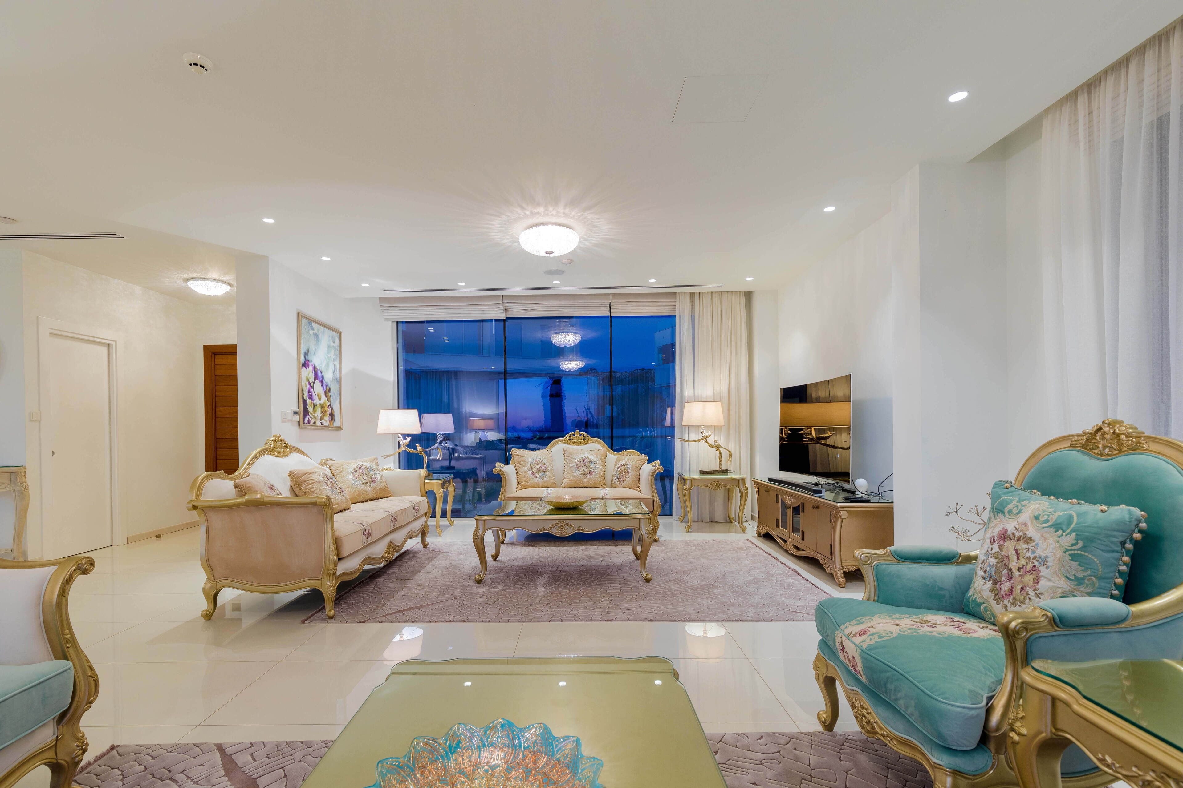 A spacious living room with a large window, a sofa, a coffee table, and a television.