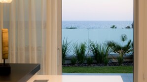 A modern kitchen with a gas stove, a pendant light, and a view of the ocean through a glass door. - Sea Pearl Beachfront Villas (Ayia Napa)