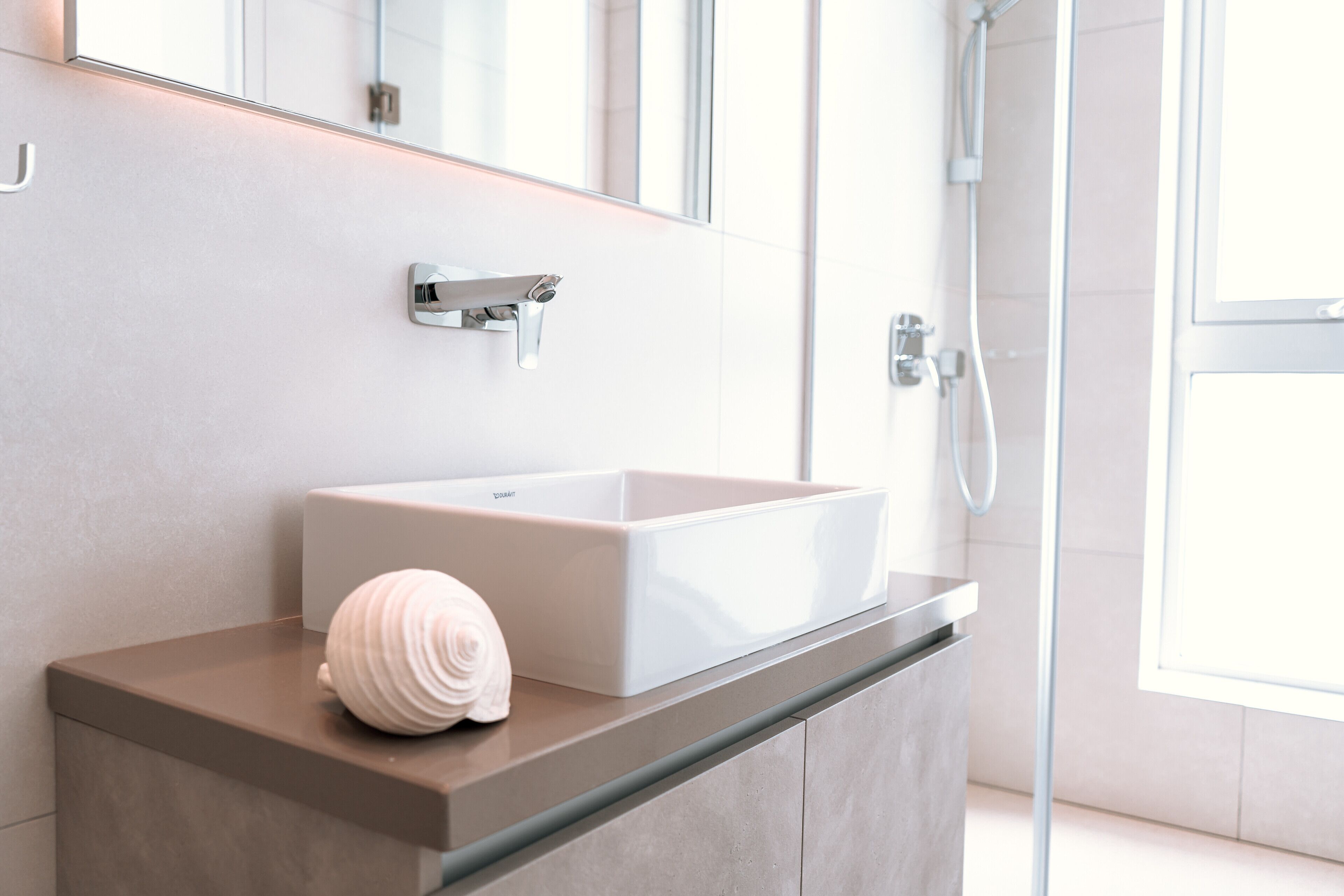 Ein modernes Badezimmer mit einem rechteckigen Waschbecken, einem Handtuch und einer Duschkabine aus Glas.
