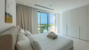 Una camera d'hotel moderna con un letto grande, vista sul mare e un balcone.