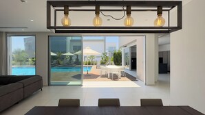 Un soggiorno moderno con vista piscina, una zona pranzo e una cucina.