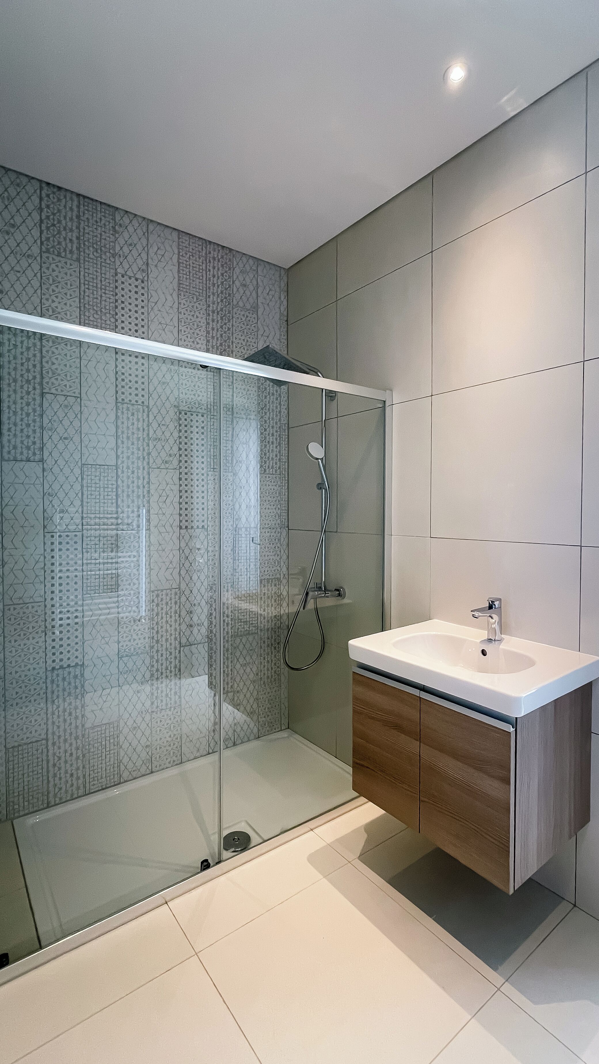 Une salle de bain moderne avec une douche à parois de verre, un meuble-lavabo en bois et un grand miroir.
