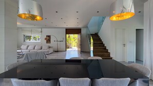 Un interior moderno con comedor, una escalera y vistas al exterior.