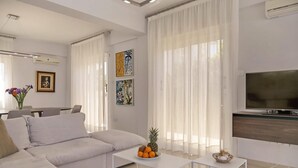 A modern living room with a sofa, a coffee table with fruit, a TV, and artwork on the wall. - Μake you feel at home. Quite location deal for Family (Paralimni)