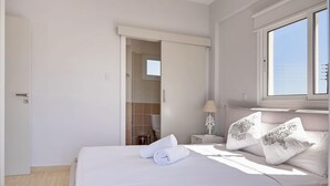 A hotel room with a bed, a nightstand, a lamp, and a window. - Μake you feel at home. Quite location deal for Family (Paralimni)