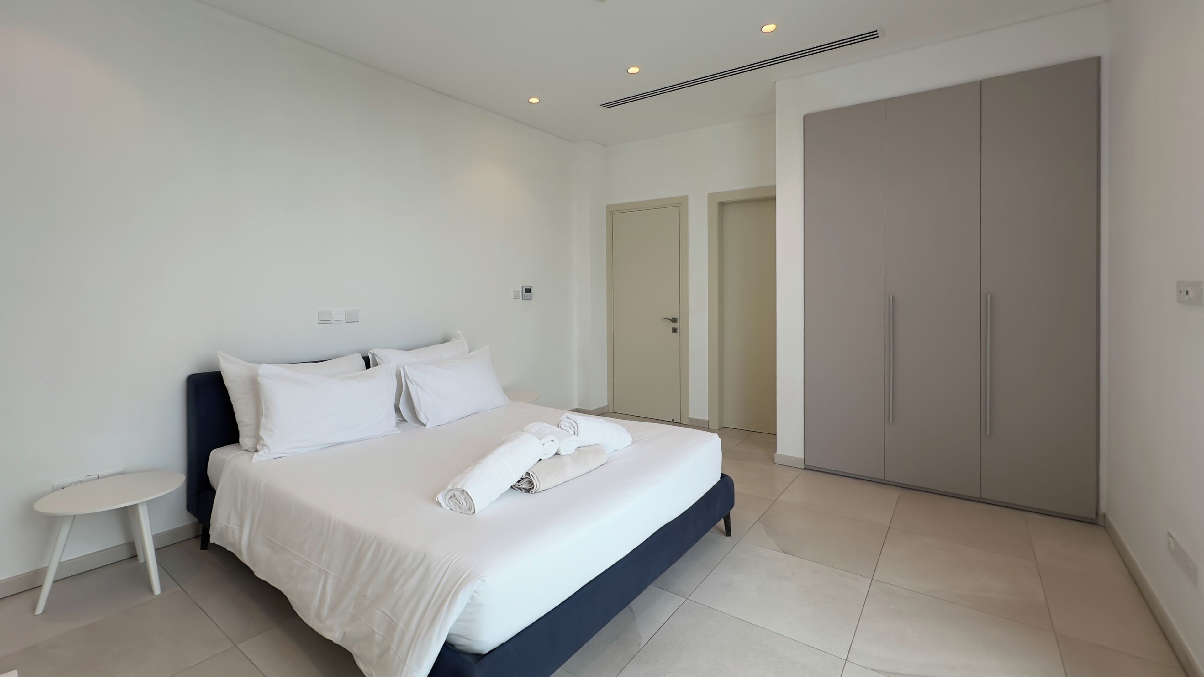 Un dormitorio moderno con cama, mesita de noche y armario.