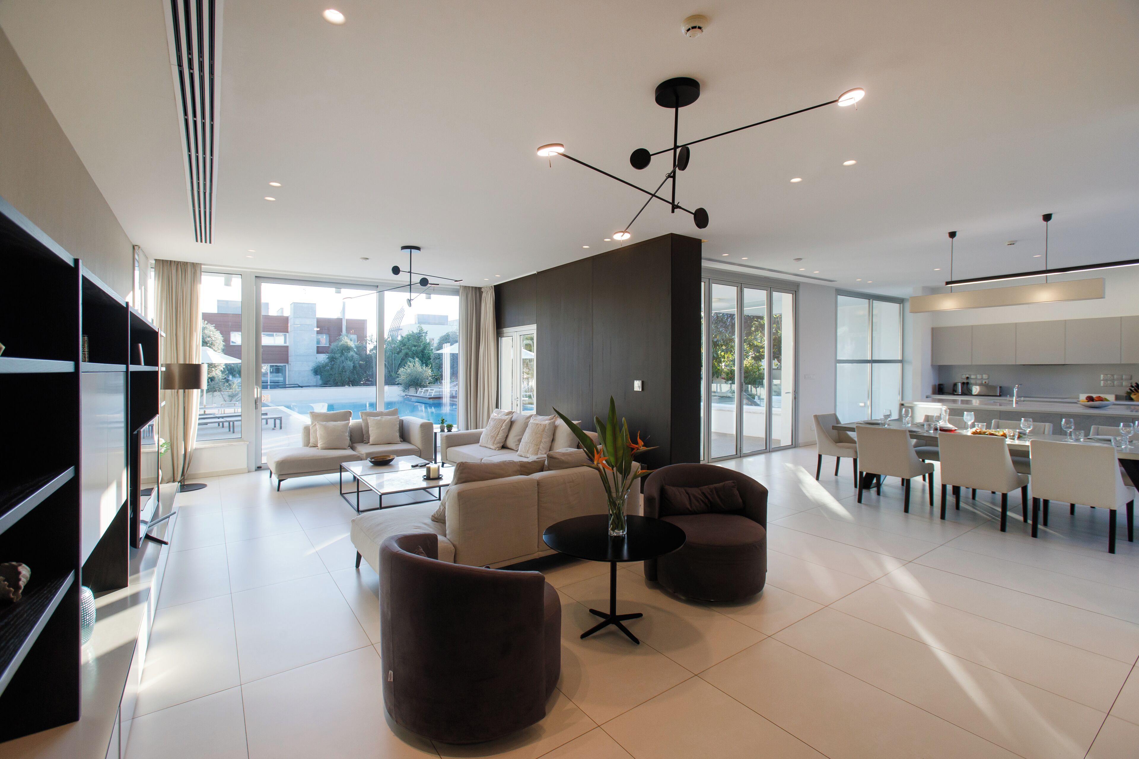 Una sala de estar moderna con sofá, sillones, una mesa de centro y un comedor con sillas y mesa.