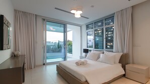 Et moderne hotelværelse med en stor seng, et skrivebord, et natbord og udsigt gennem glasdøren.
