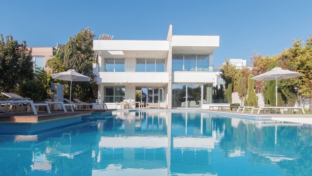 Et moderne hotel med en stor swimmingpool, liggestole og parasoller.