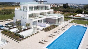 A modern two-story building with a rooftop terrace, a swimming pool, and a landscaped garden.