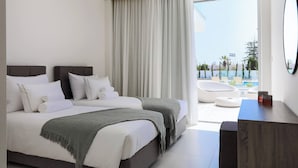 A modern hotel room with a large bed, a desk, and a view of the pool area.