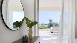 A modern room with a large mirror, a potted plant, and a view of a balcony with outdoor furniture.