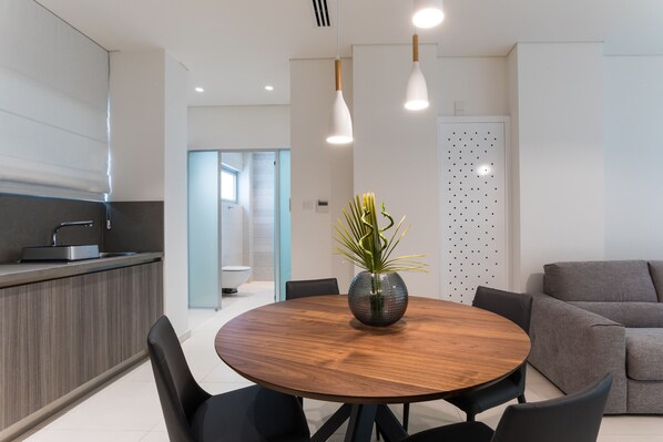 Una cocina moderna con una mesa redonda de madera, sillas negras e iluminación colgante.
