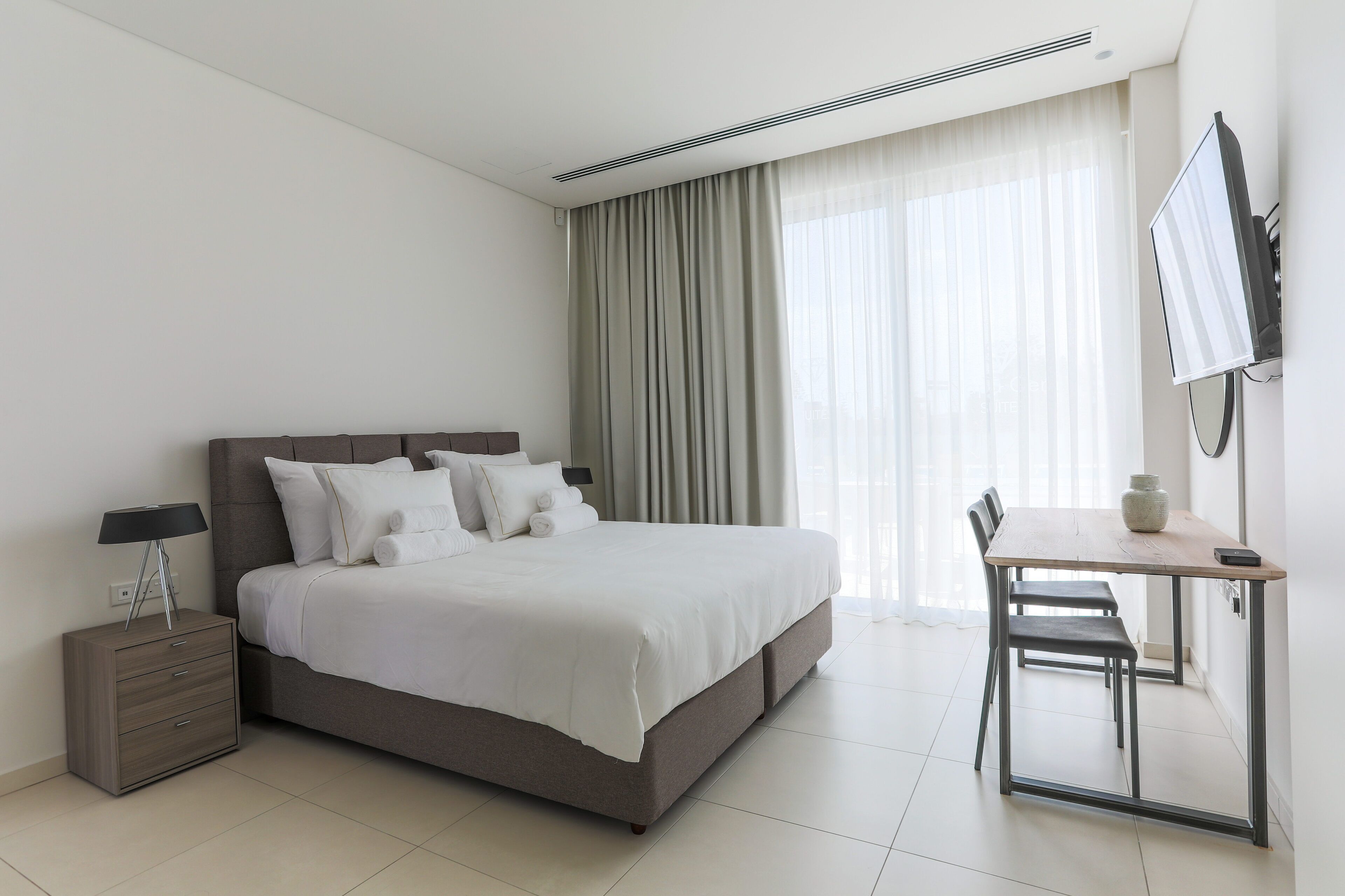 Una habitación de hotel moderna con una cama grande, un escritorio y un televisor.