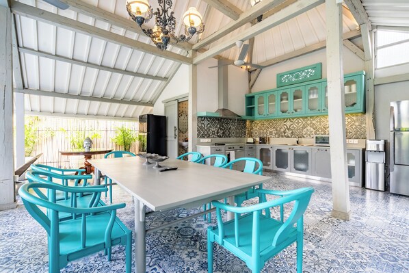 A spacious kitchen with turquoise cabinets, a large dining table with chairs, and patterned flooring.