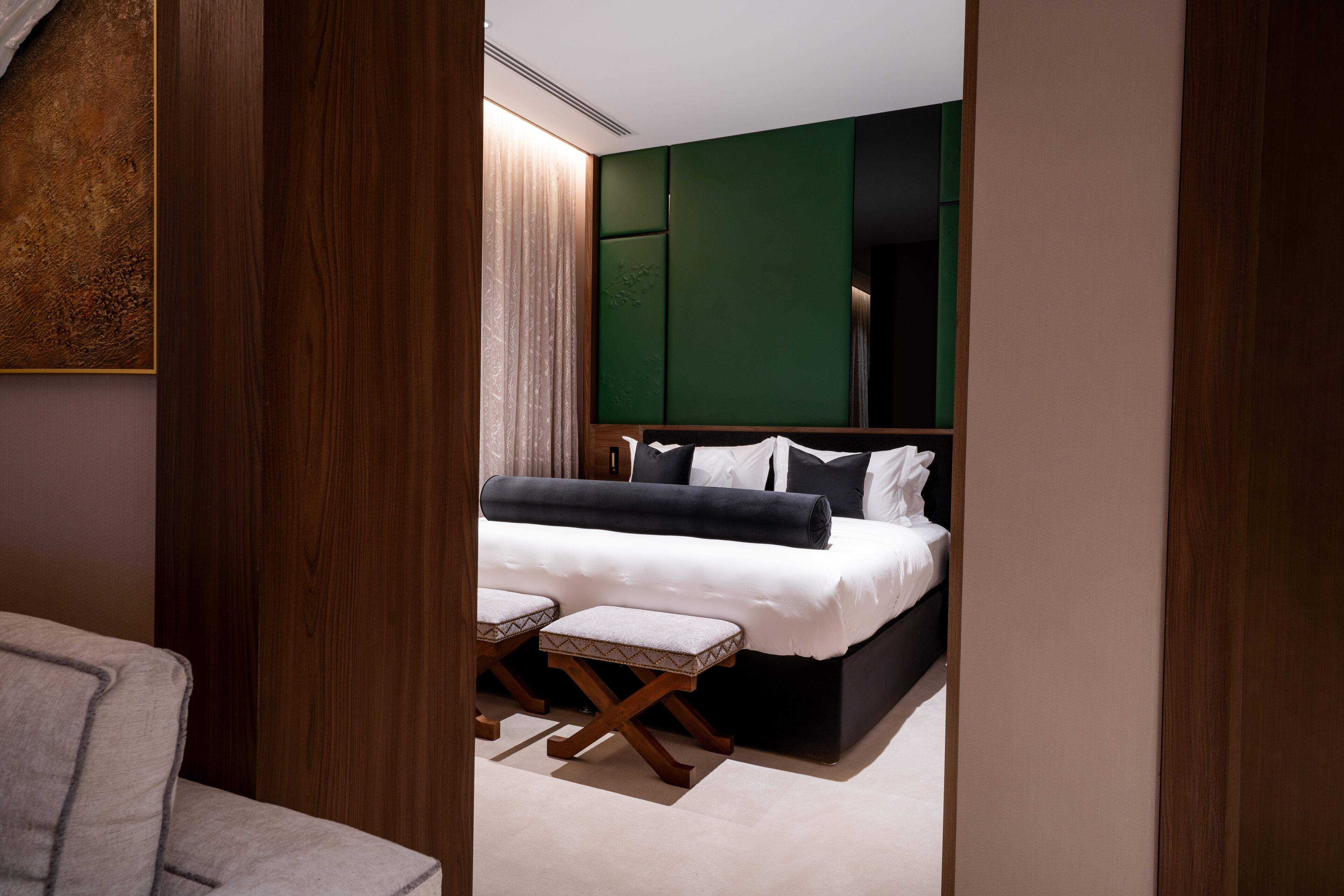 Una habitación de hotel moderna con una cama grande, un área de descanso pequeña y una pared verde decorativa.