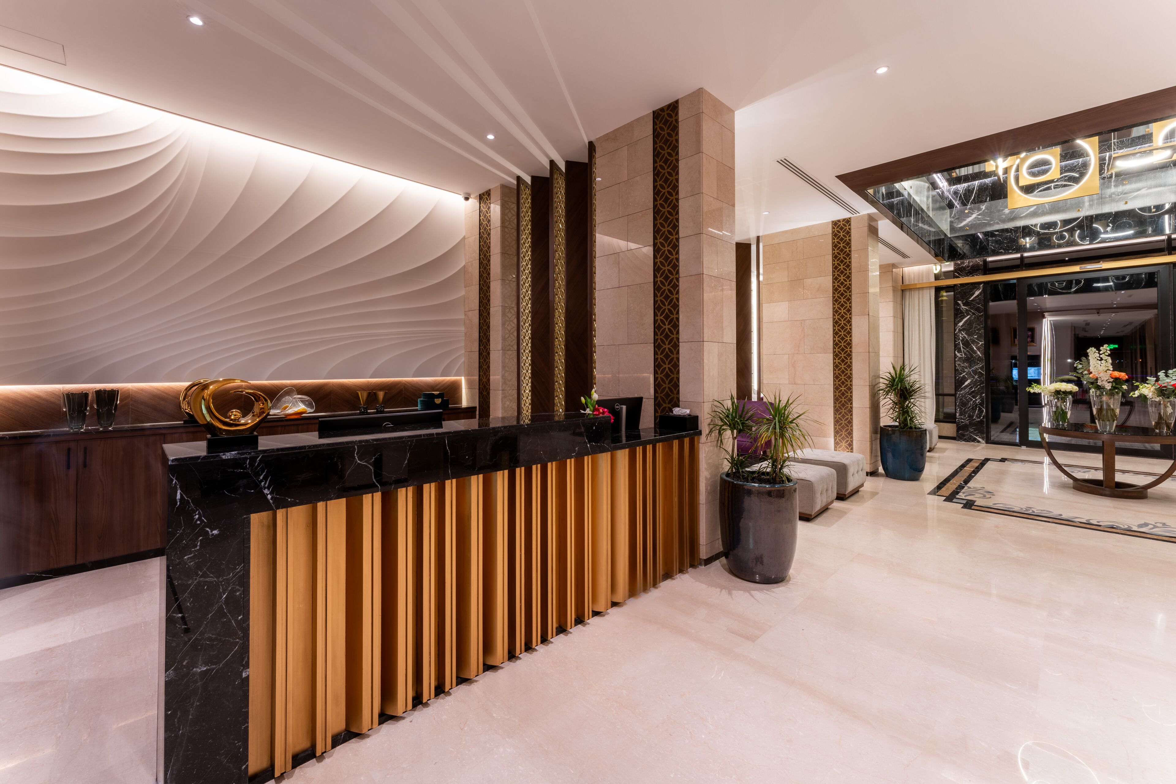 Un área de recepción moderna con una barra de mármol negro, listones de madera verticales y una pared con diseño.