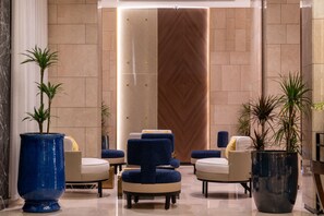 A modern lobby with seating areas, large potted plants, and a decorative wall. - Lilac Park Hotel (Tabuk)