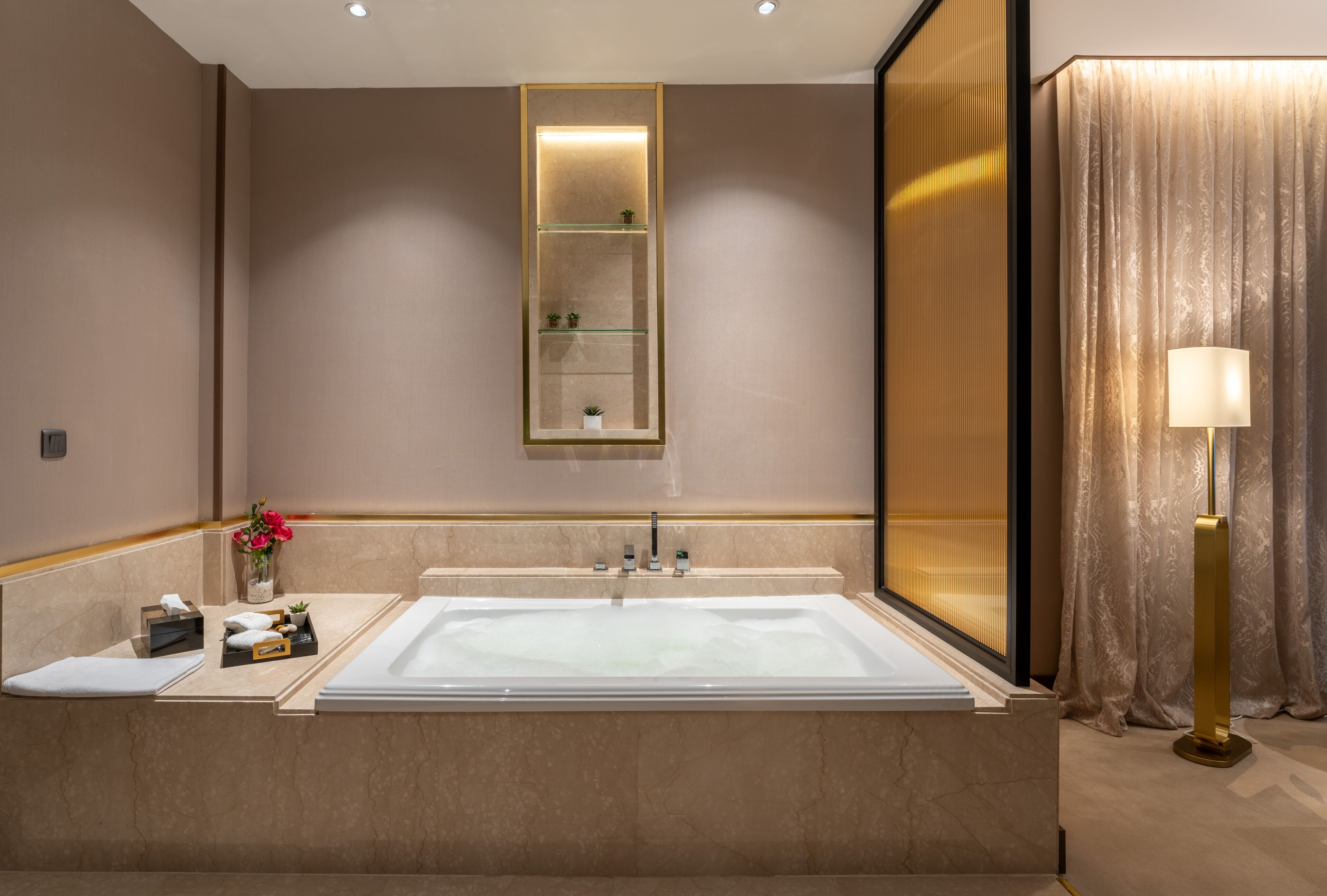 Ein modernes Badezimmer mit einer großen Badewanne, einem Spiegel mit Ablageflächen und einer Stehlampe.
