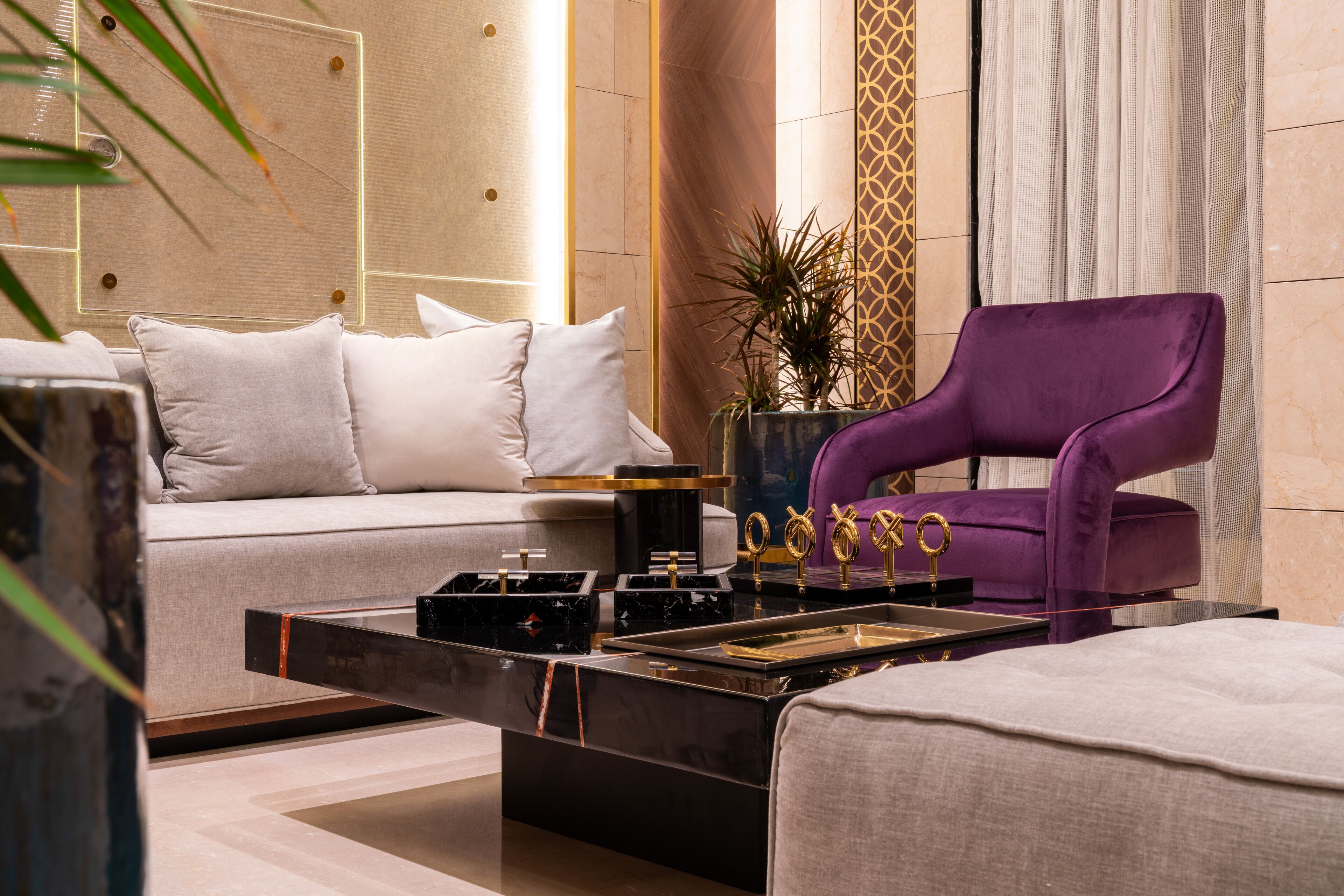 Una sala de estar moderna con un sofá, un sillón morado, una mesa de centro y objetos decorativos.