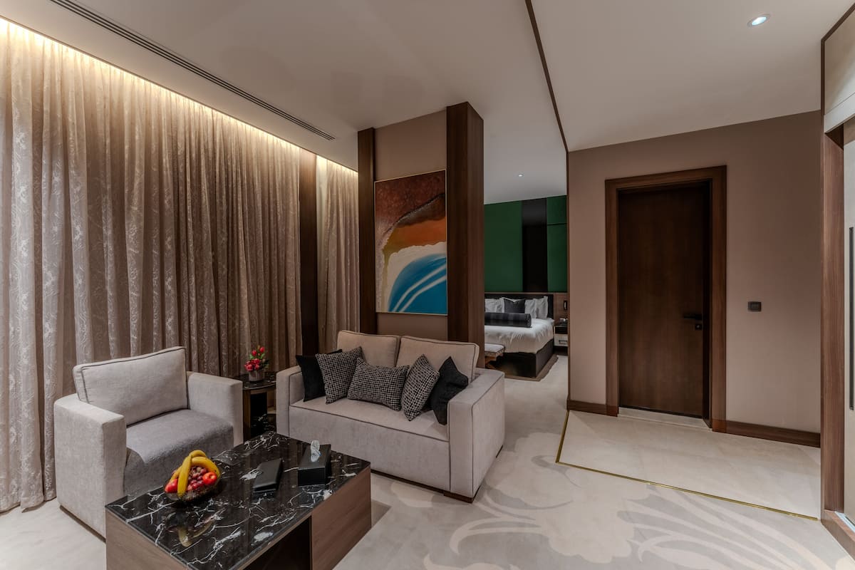 A modern living room with a sofa, armchairs, a coffee table, and a painting on the wall.