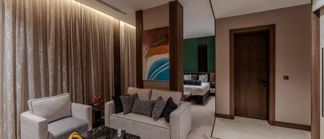 A modern living room with a sofa, armchairs, a coffee table, and a painting on the wall.