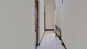 A narrow, tiled corridor with a metal railing on one side and a door on the other. - OYO Life 92685 Kost Arimbi (Bandung)