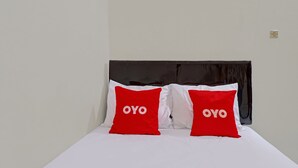 A bed with white bedding and two red pillows with the word "OYO" on them. - OYO Life 92685 Kost Arimbi (Bandung)