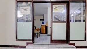 A building entrance with glass doors, a sign indicating CCTV surveillance, and a tiled floor. - OYO Life 92685 Kost Arimbi (Bandung)
