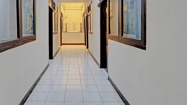 A corridor with tiled flooring and large windows on both sides. - OYO Life 92685 Kost Arimbi (Bandung)