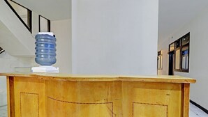 A wooden reception desk with a large water dispenser and a white device on top. - OYO Life 92685 Kost Arimbi (Bandung)