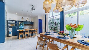Une cuisine moderne avec une porte bleue, des chaises en bois et une table à manger dressée pour six personnes.