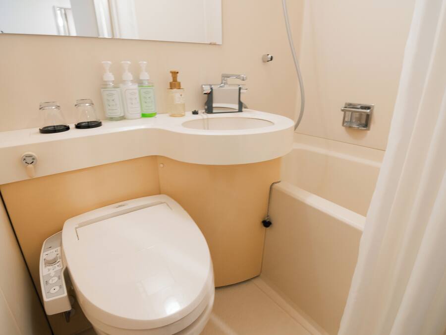 A compact bathroom with a toilet, sink, and a mirror above the sink.