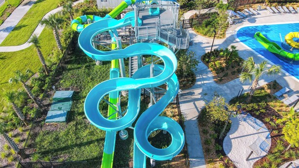 A water park with a large blue water slide, a pool, and a parking lot.